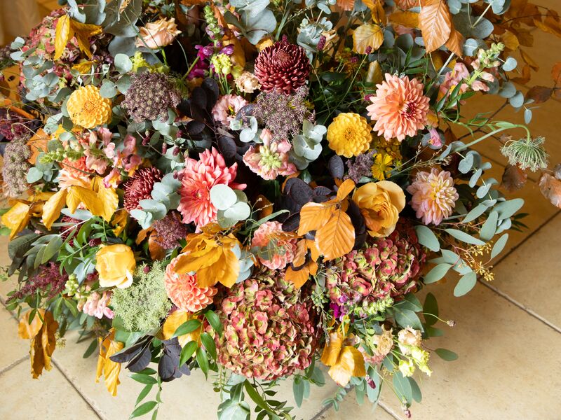 Wild autumn flower arrangement beside Ellie and Jack’s green welcome sign