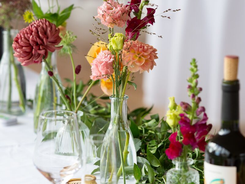 Autumn dahlias, roses and snapdragons arranged in bud vases on a reception table