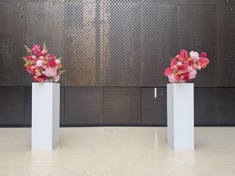 Pink floral ceremony installations at Hackney Town Hall Two sculptural pink and coral ceremony arrangements on white plinths in Hackney Town Hall