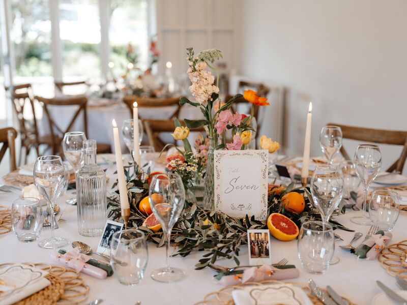 Hyde House reception table styled with colourful bud vases, olive foliage and citrus
