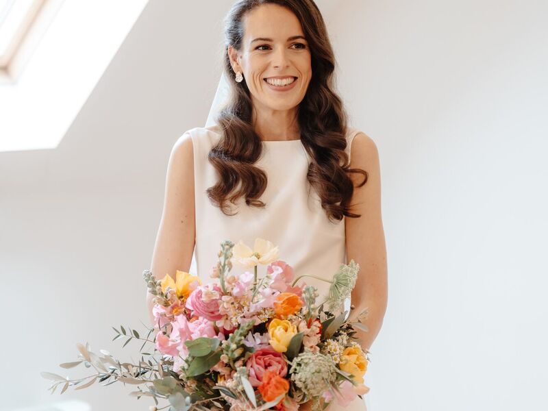 Holly holding her colourful spring bouquet of pink, peach and orange flowers