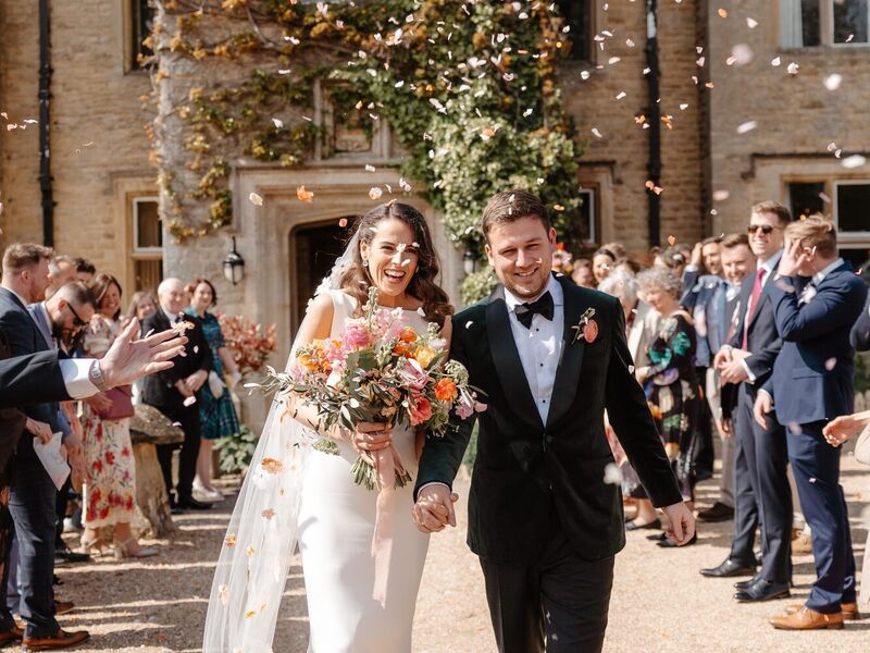 Holly and Mick leaving Hyde House with Holly's colourful spring bridal bouquet