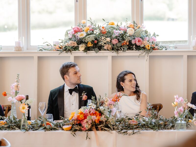 Repurposed altar flowers displayed behind Holly and Mick’s wedding top table