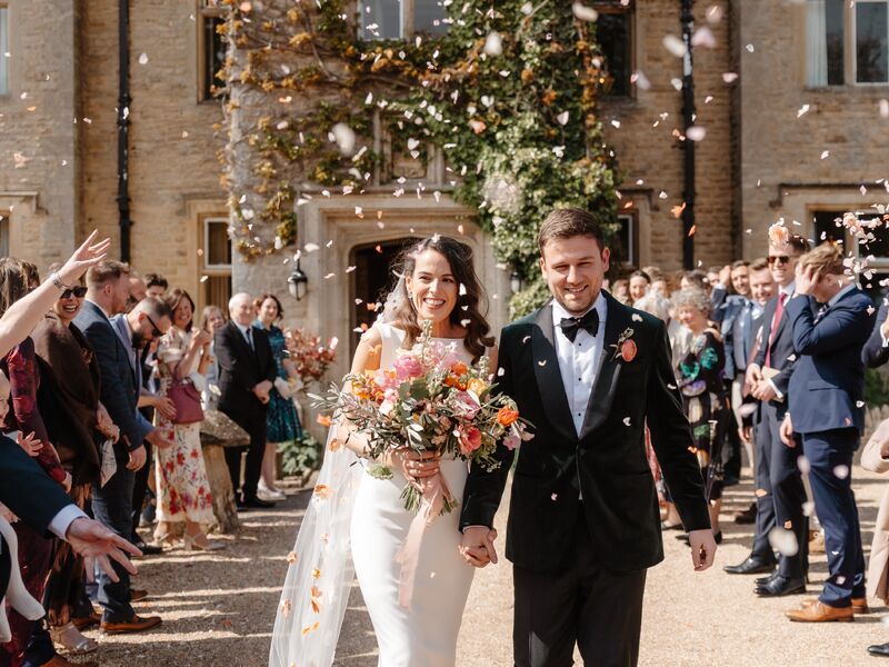 Holly and Mick celebrating outside Hyde House with colourful spring wedding flowers