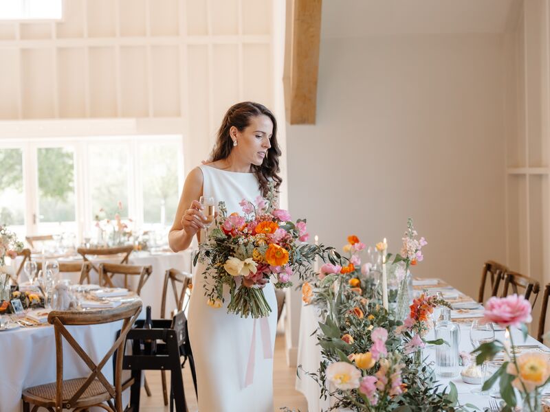 Holly beside reception tables styled with colourful flowers, citrus and olive foliage