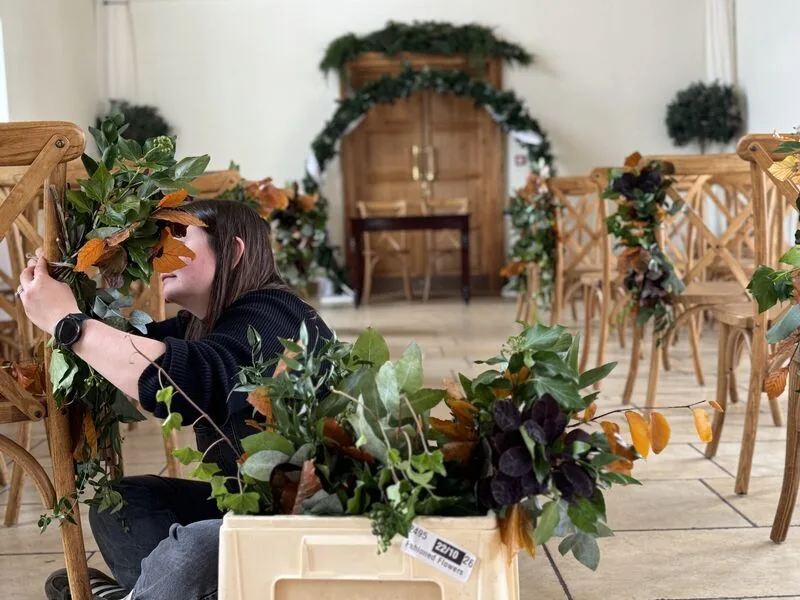 Florist preparing autumn wedding flowers during venue setup at Delbury Hall