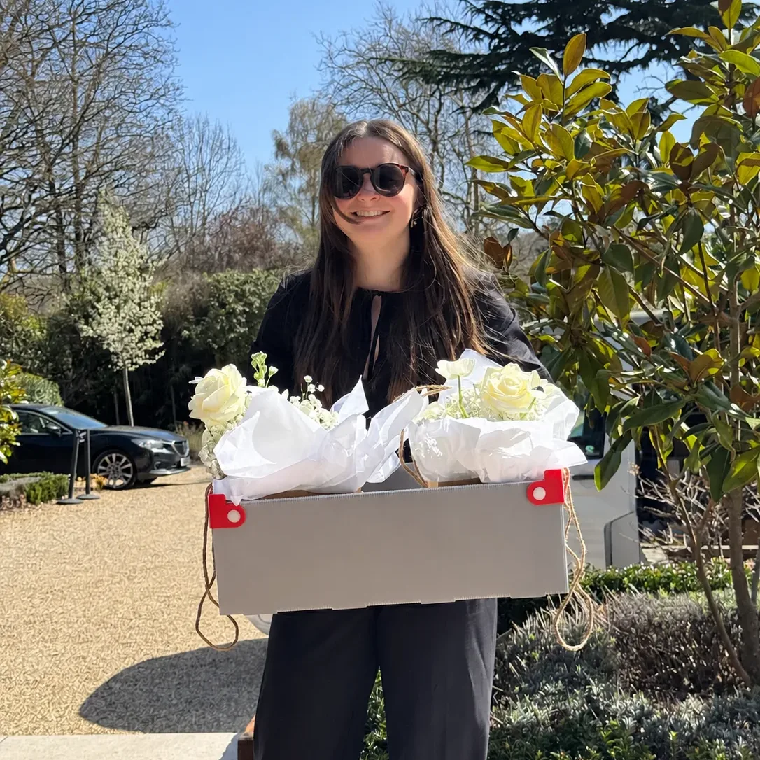 Alex delivering boxed white wedding flowers to a venue