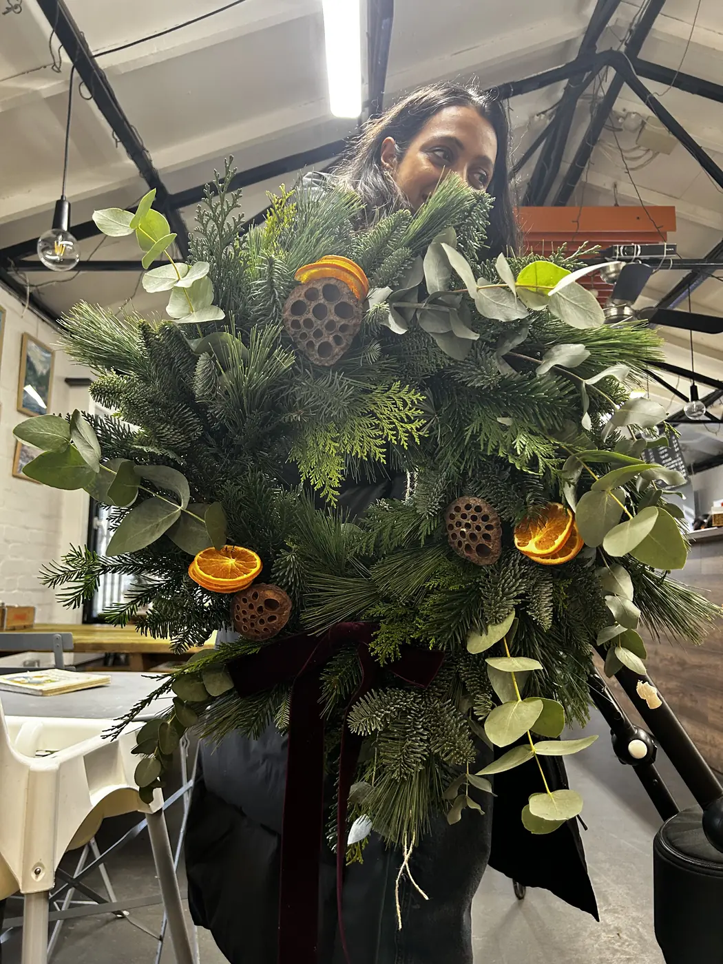 Guest holding a finished natural Christmas wreath decorated with dried citrus
