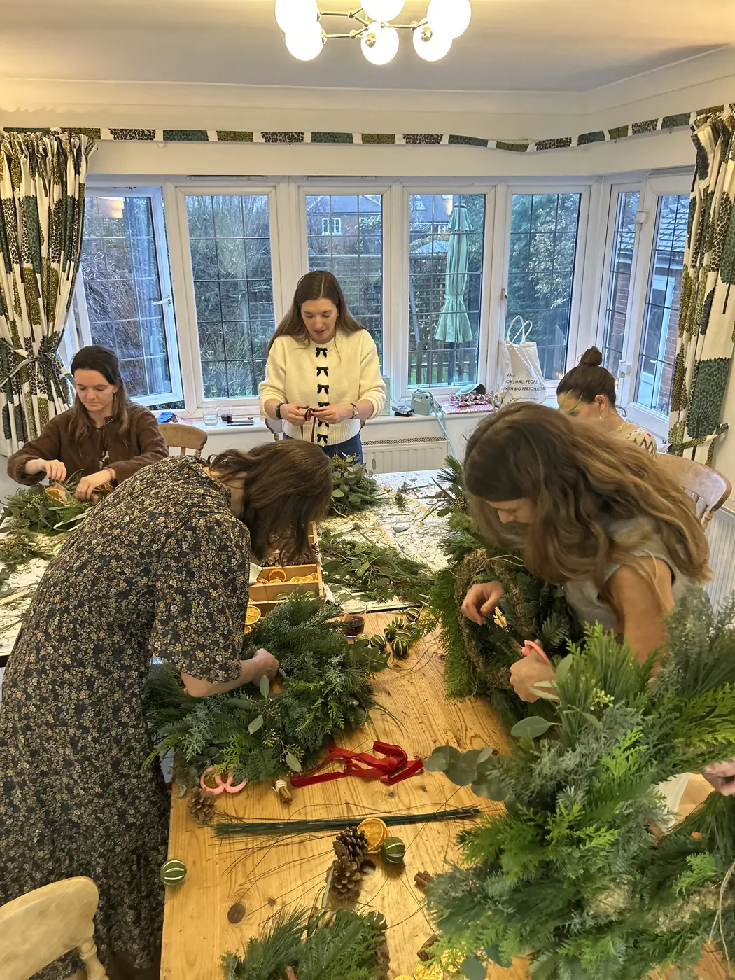 Guests making natural Christmas wreaths together around a workshop table
