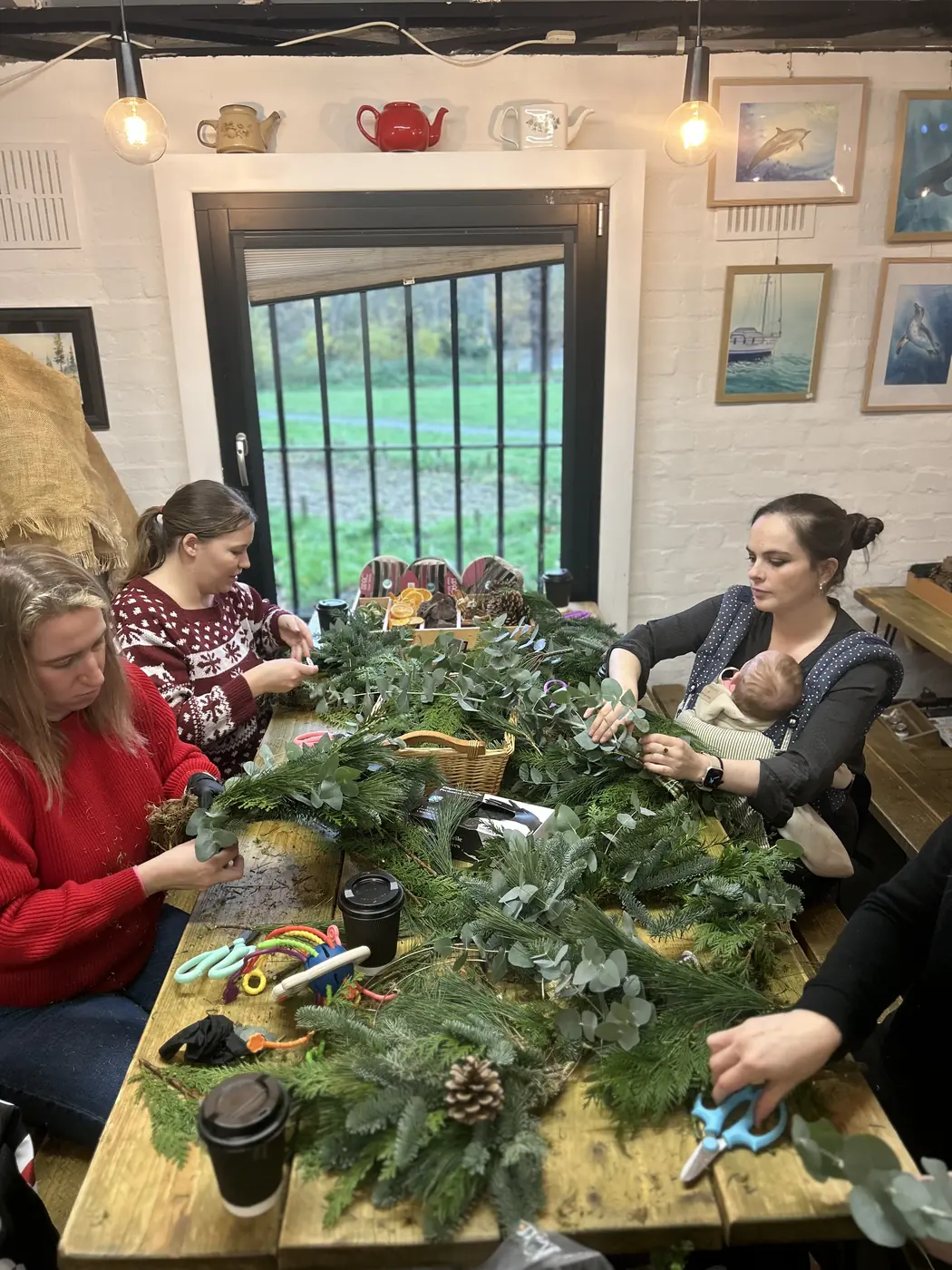 Parents making natural Christmas wreaths with a baby at a relaxed workshop